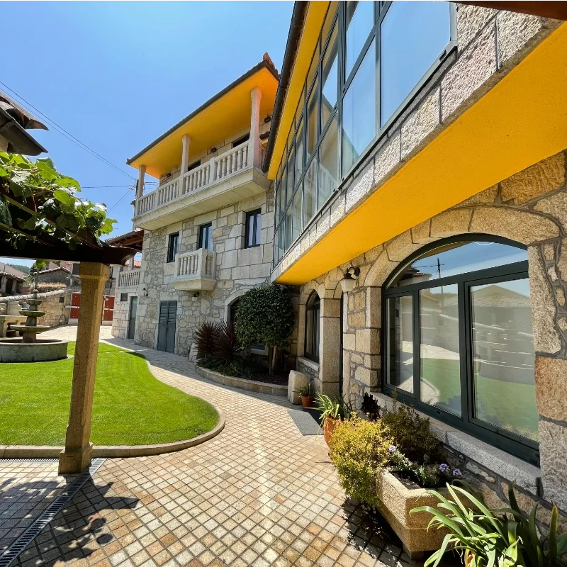 Fachada tradicional de piedra y jardín cuidado en nuestro alojamiento en Sober.