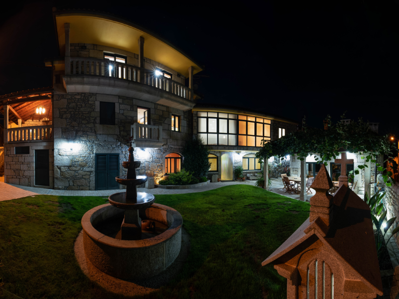 Fachada de piedra iluminada de noche de Apartamentos Río Sil en Sober, Ribeira Sacra.