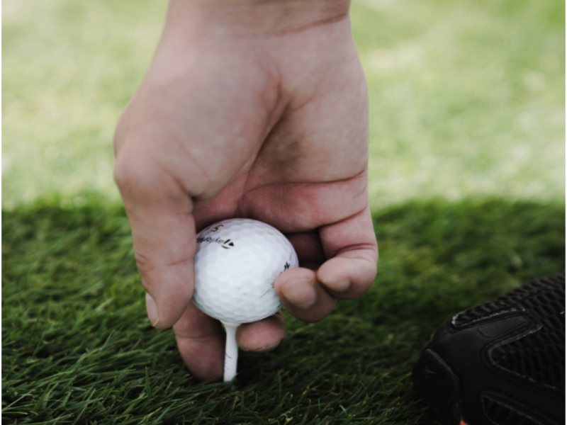 Persona colocando una bola de golf en el campo de Pantón.