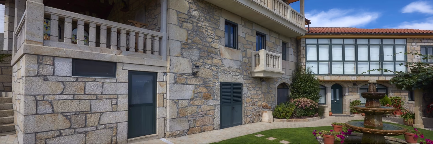 Fachada principal de piedra y balcones de Apartamentos Río Sil, Sober.