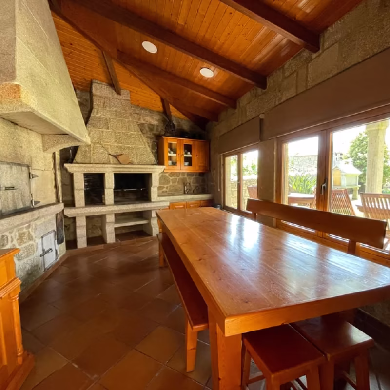 Asador comunitario con horno de leña y barbacoa interior en Apartamentos Río Sil.