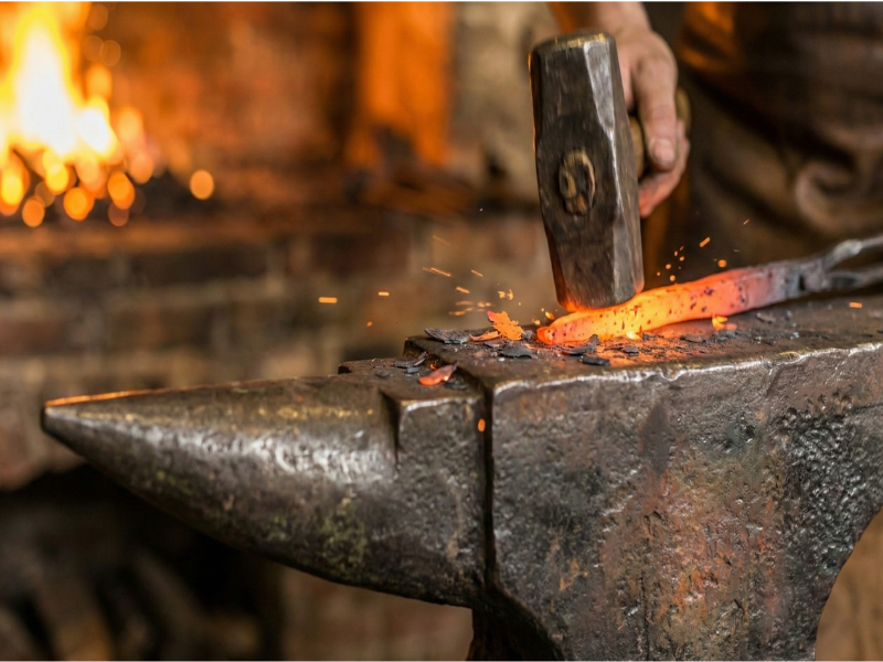 Herrero trabajando el metal al rojo vivo en la fragua.