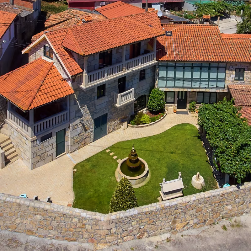 Jardín y fachada de piedra de Apartamentos Río Sil, casa rural con encanto en la Ribeira Sacra.